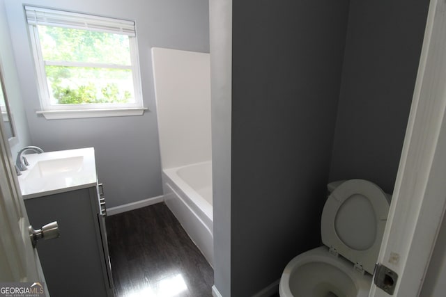 bathroom featuring wood-type flooring, a washtub, vanity, and toilet