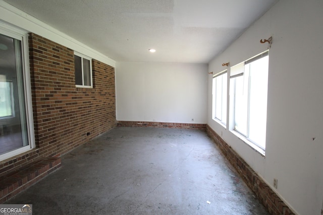 unfurnished room featuring concrete floors and brick wall