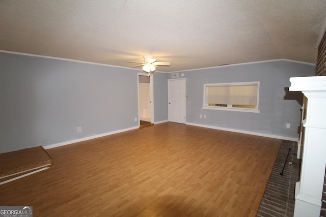 unfurnished living room with ornamental molding, ceiling fan, a brick fireplace, and hardwood / wood-style flooring