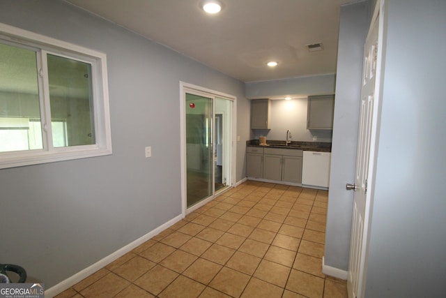 kitchen featuring sink, dishwasher, gray cabinets, and light tile patterned floors