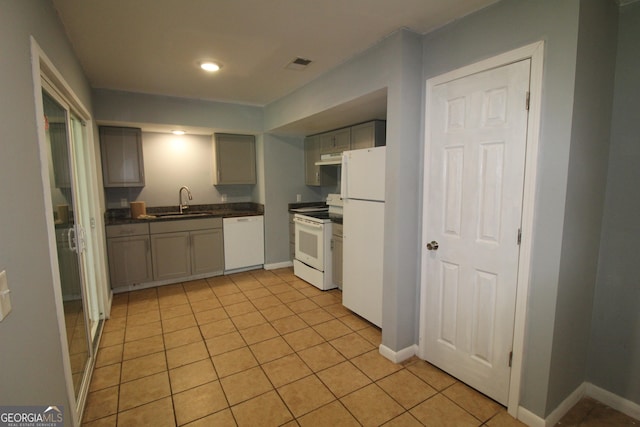 kitchen featuring sink, white appliances, light tile patterned flooring, and gray cabinetry