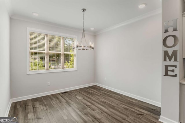 unfurnished dining area featuring dark hardwood / wood-style flooring, an inviting chandelier, and ornamental molding