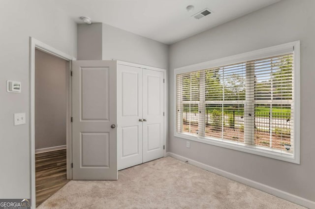 unfurnished bedroom featuring light colored carpet and a closet