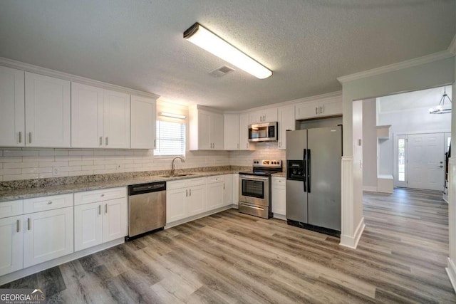 kitchen featuring light stone countertops, white cabinetry, a textured ceiling, and appliances with stainless steel finishes