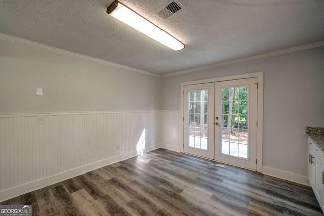 empty room with a textured ceiling, french doors, crown molding, and dark hardwood / wood-style flooring