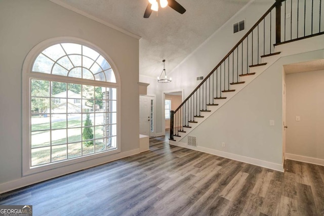 foyer featuring ceiling fan with notable chandelier, a textured ceiling, ornamental molding, and dark hardwood / wood-style floors