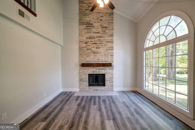 unfurnished living room with a fireplace, high vaulted ceiling, crown molding, and plenty of natural light