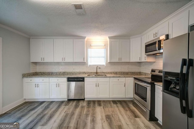 kitchen with stainless steel appliances, light stone countertops, a textured ceiling, sink, and white cabinetry