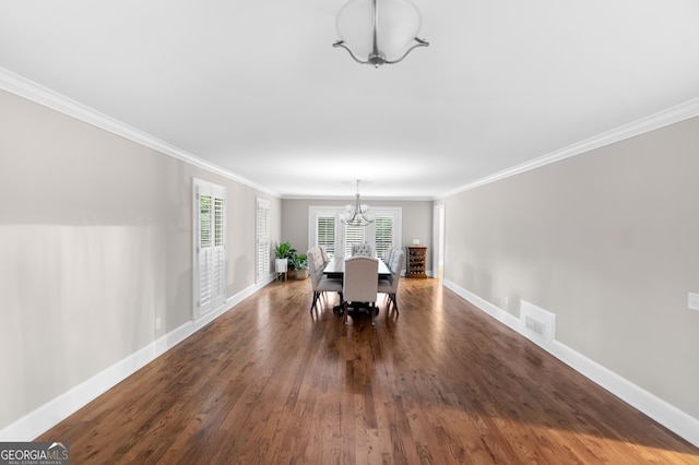 dining room with a notable chandelier, crown molding, and dark hardwood / wood-style floors