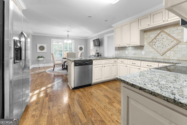 kitchen featuring pendant lighting, stainless steel appliances, tasteful backsplash, hardwood / wood-style floors, and white cabinets