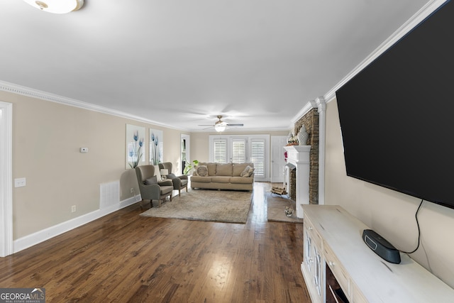 living room featuring a fireplace, ceiling fan, crown molding, and dark wood-type flooring