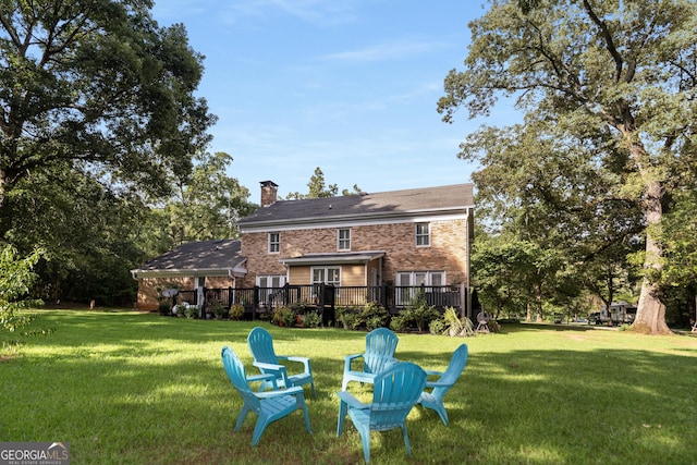 rear view of property featuring a lawn and a deck