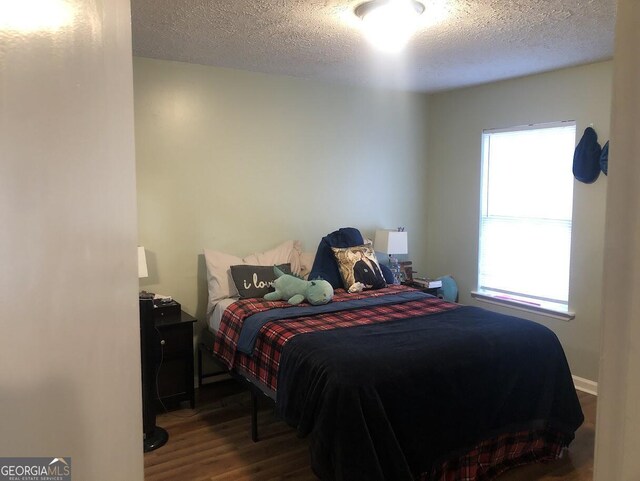 bedroom with wood-type flooring, a textured ceiling, and multiple windows