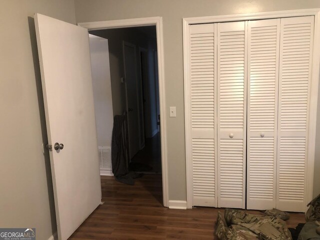 bedroom with dark wood-type flooring and a closet