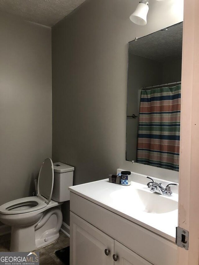 bathroom with toilet, a textured ceiling, and vanity