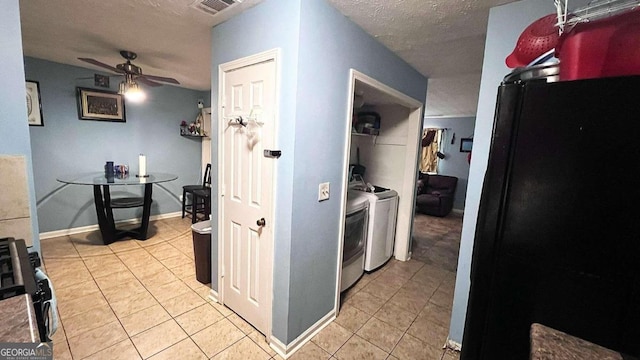 kitchen featuring washer and dryer, light tile patterned floors, ceiling fan, black fridge, and a textured ceiling