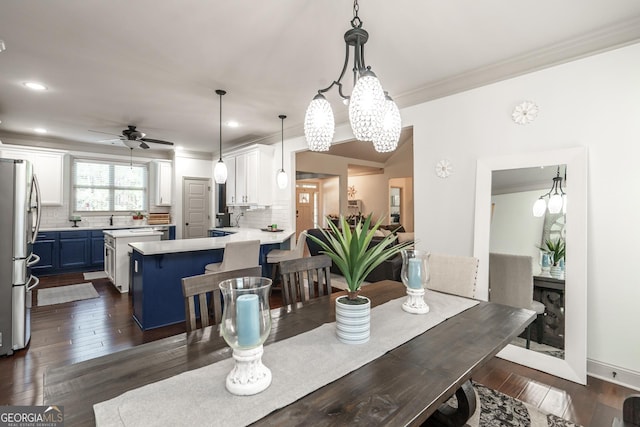 dining area featuring ceiling fan with notable chandelier, dark wood-type flooring, and ornamental molding