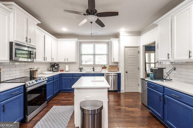 kitchen featuring sink, blue cabinets, a center island, tasteful backsplash, and appliances with stainless steel finishes