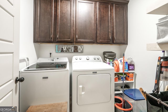 clothes washing area featuring washer and dryer and cabinets