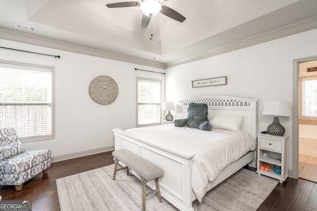 bedroom with ensuite bathroom, a raised ceiling, ceiling fan, and dark wood-type flooring