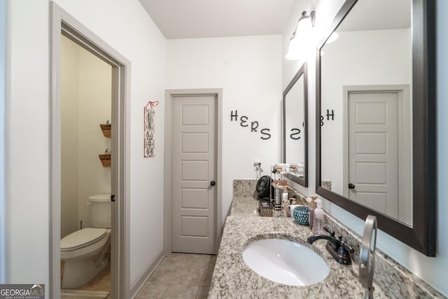 bathroom with toilet, vanity, and tile patterned floors