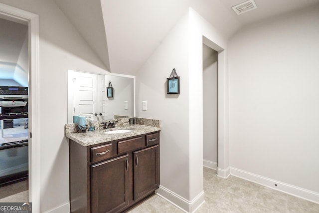 bathroom with lofted ceiling, vanity, and tile patterned flooring