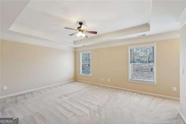 carpeted spare room with ceiling fan, a tray ceiling, and crown molding