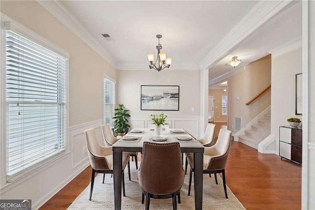 dining space with wood-type flooring, a notable chandelier, and crown molding