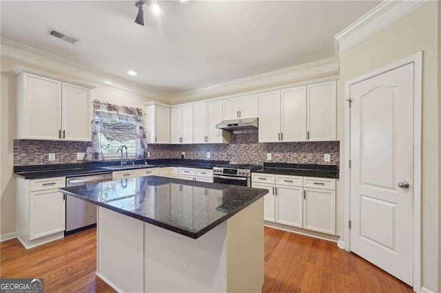 kitchen featuring appliances with stainless steel finishes, a kitchen island, hardwood / wood-style flooring, white cabinets, and sink