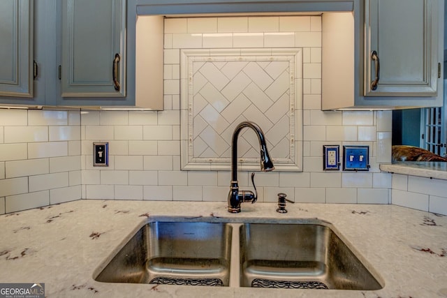 kitchen with sink, light stone counters, and decorative backsplash