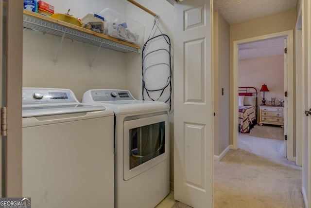 clothes washing area with light colored carpet, separate washer and dryer, and a textured ceiling