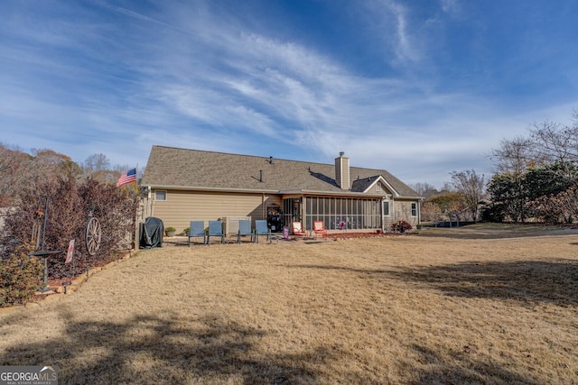 rear view of property featuring a yard and a sunroom