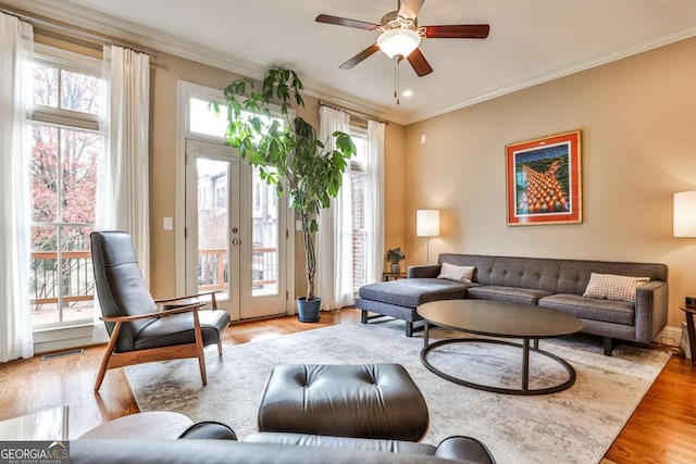 living room with french doors, ceiling fan, light hardwood / wood-style floors, and crown molding