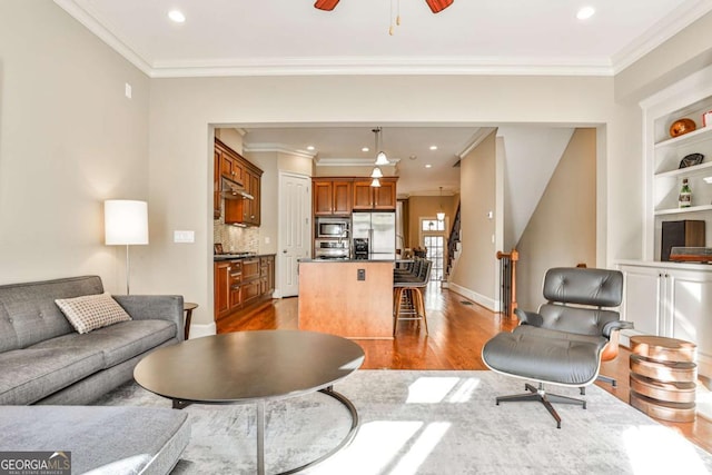 living room with hardwood / wood-style floors, ceiling fan, and crown molding