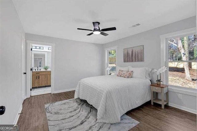 bedroom with connected bathroom, dark hardwood / wood-style flooring, and ceiling fan