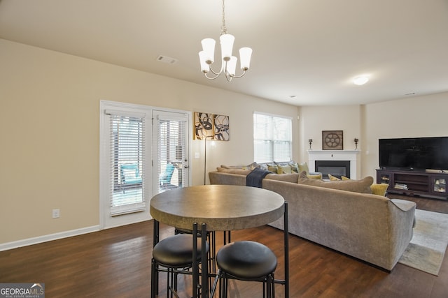 dining space with plenty of natural light, an inviting chandelier, and dark hardwood / wood-style floors