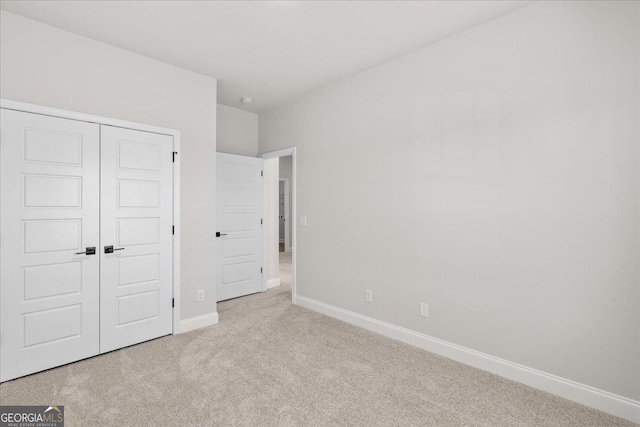 unfurnished bedroom with light colored carpet and a closet