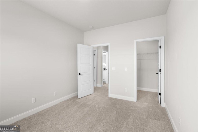 unfurnished bedroom featuring a spacious closet, light carpet, and a closet