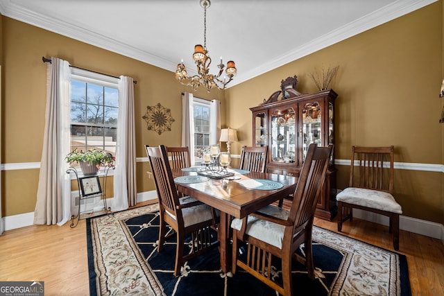 dining area with light hardwood / wood-style floors, crown molding, and a chandelier