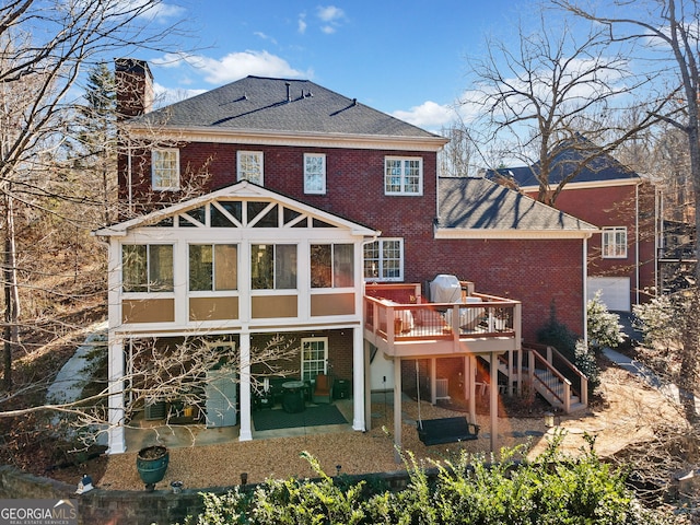 rear view of house with a patio, a wooden deck, and a sunroom