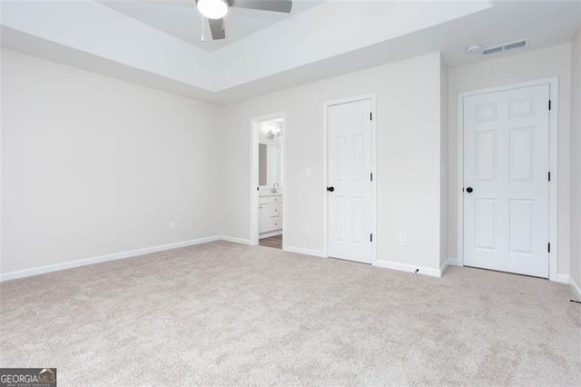 unfurnished bedroom with connected bathroom, ceiling fan, and light colored carpet