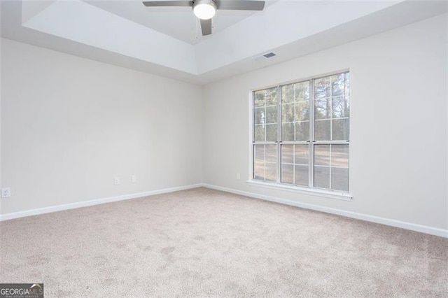 spare room with ceiling fan, a raised ceiling, and carpet floors