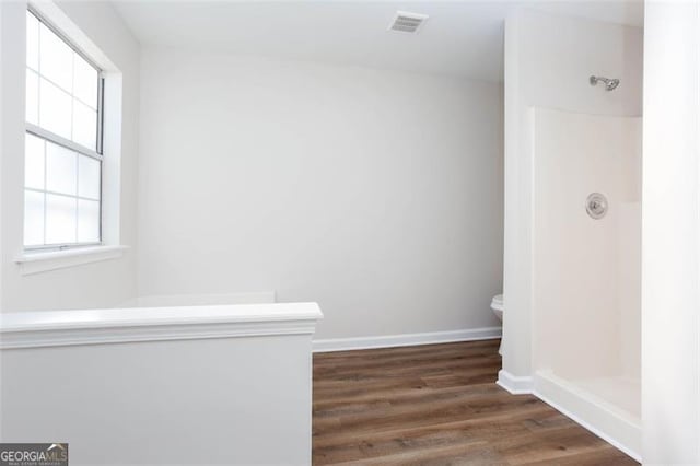 bathroom featuring walk in shower, toilet, and hardwood / wood-style flooring