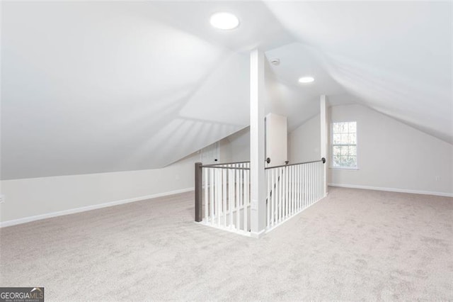 additional living space featuring lofted ceiling and light carpet