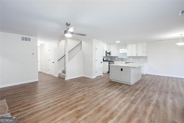 kitchen with hardwood / wood-style flooring, a kitchen island, white cabinetry, appliances with stainless steel finishes, and ceiling fan