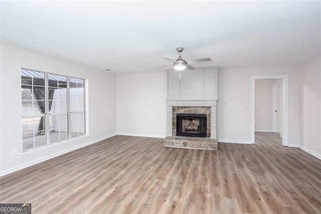 4100 Chanticleer Dr, Kennesaw, GA 30152 - unfurnished living room with wood finished floors, baseboards, ceiling fan, and a stone fireplace