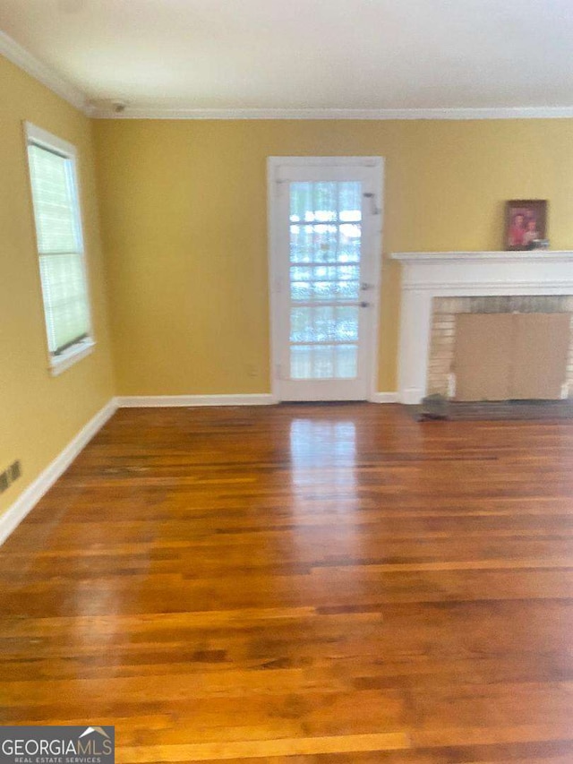 unfurnished living room with wood-type flooring, a fireplace, and ornamental molding