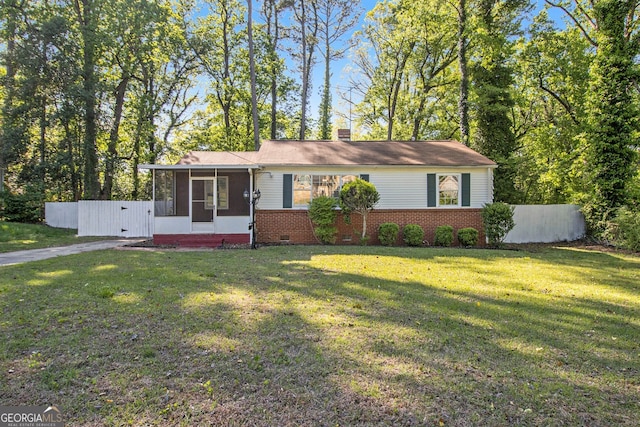 view of front facade with a sunroom, a chimney, a front yard, and fence