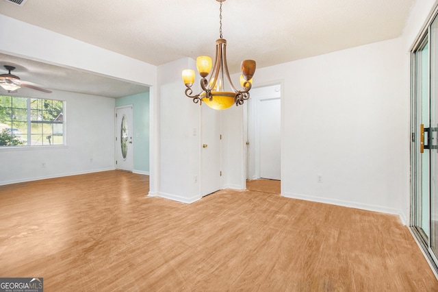 unfurnished dining area with ceiling fan with notable chandelier, light wood-style flooring, and baseboards