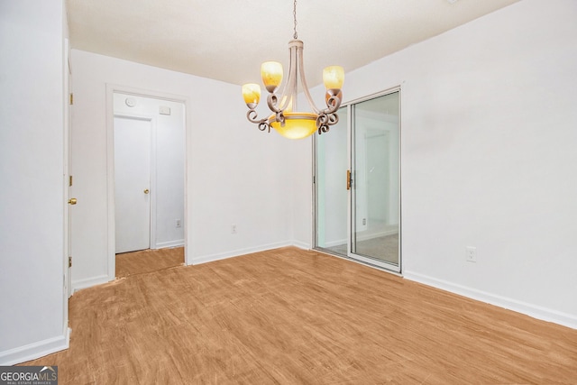 spare room with baseboards and a notable chandelier